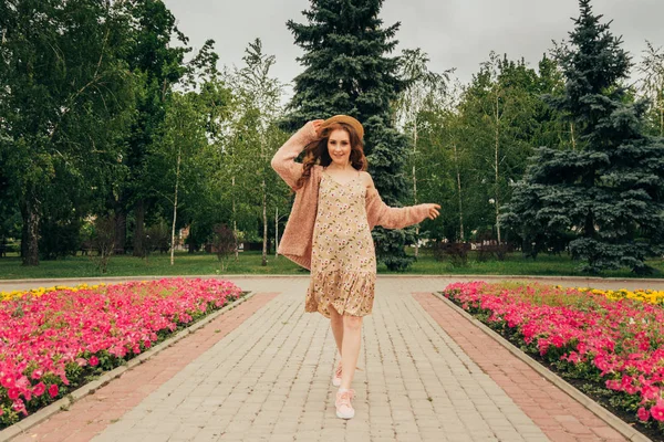 Mutlu kız elbise ve şapka bir şehir sokak ve kamera bakarak gülümsüyordu. bir şapka, bir çiçek ve sıcak renk bir ceket elbise