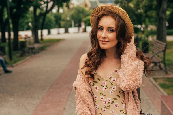 행복 한 여자 드레스와 모자 도시 거리 고 카메라에 웃 고. 모자, 꽃 그리고 따뜻한 색상의 재킷에 드레스에 — 스톡 사진