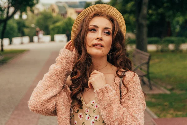 Smiling happy girl in dress and hat on a city street and looking at camera. in a hat, a dress in a flower and a jacket of warm colors — Stock Photo, Image