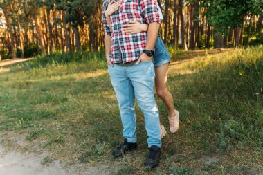 af diliyorum. kız adam arkadan sarılma. kin, kavga. bir ekose gömlek ve kot kolunu, bir kız beyaz bir bluz ve şort saat takan bir adam. Yaz saati. ormanda yürümek. Onu arkadan kisses