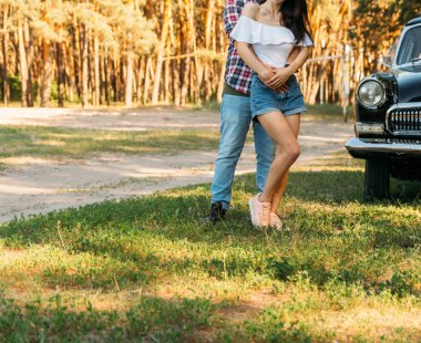 adam arkasında ve kız hugs, birlikte eller. arkasında siyah bir car.holding yaz aylarında eller var. bir adam elinde siyah bir saati var. Yaz aylarında tarihi