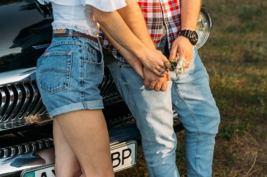 bir erkek ve bir kadın, elinde bir saat ile bir çiçek ile elele gövde. ayakta car.check gömlek, şort ve kot pantolon, beyaz bluz