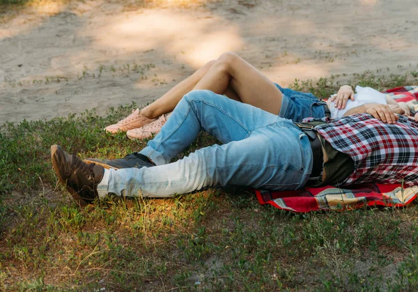 男と少女は 夏に芝生の上の格子縞格子縞に横たわっています 格子縞のシャツ ショート パンツ ジーンズ 白のブラウスに身を包んだ — ストック写真