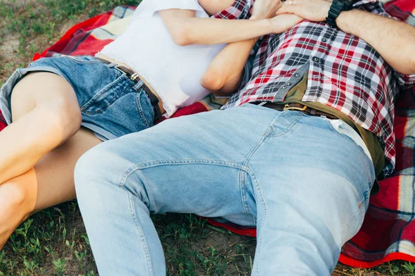 这家伙和那个女孩在夏天躺在草地上的格子格子上 穿着格子衫 短裤和牛仔裤 白色上衣 — 图库照片