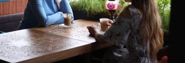 girlfriends enjoying in cafe together. Young women meeting in a cafe.meeting two women in a cafe for coffee. blue dress, dress in a flower, on a carved table is a cups of coffee and a lamp.drink coffee