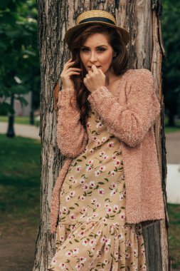 bir ağacın yanında duran güzel bir kızın portresi. yaz, Doğa, vintage elbise ve bej sweater.in şapka romantizm Kızıl saçlı kız yürümek ve flört