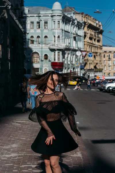 Mooie brunette wervelingen, dansen op een straat in het midden van de stad, lacht, lacht, geluk, plezier — Stockfoto
