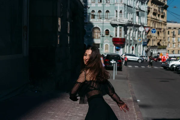 Hermosa morena gira, baila en una calle en el centro de la ciudad, ríe, sonríe, felicidad, diversión —  Fotos de Stock