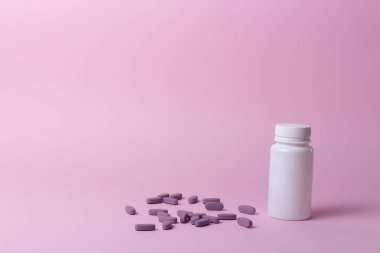 bir beyaz hap şişesi üzerinde pembe bir arka plan. depolama hapları. vitaminler. hapları bırakın. ve mor haplar, haplar yalan birbirine yakın.