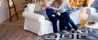 Aile Noel ağacı yakınındaki kanepede. Geleneksel şömine ile dekore edilmiş salon. Sıcak sıcak kış akşam evde.