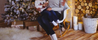 Aile Noel ağacı yakınındaki sandalyeye. Geleneksel şömine ile dekore edilmiş salon. Rahat sıcak kış akşamları home.the çocuk bir yılbaşı oyuncak tutuyor