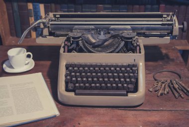 Eski daktilo masaya yanında kitap yatıyor ve bir kupa olduğunu