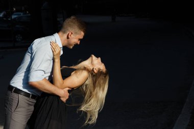 kız ve adam, üzerinde bükme gülümsüyor musun, adam kız öpmek istiyor. yüzlerinde güneş parlar. sert ışık ile atış karanlık bir arka plan üstüne.