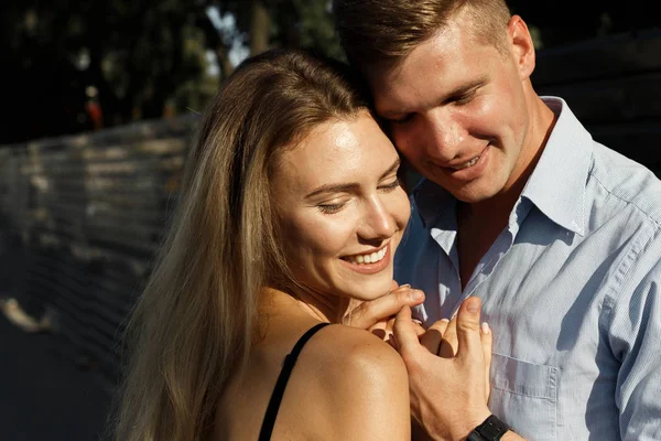 Das Mädchen und der Kerl lächeln Hand in Hand und umarmen sich. — Stockfoto