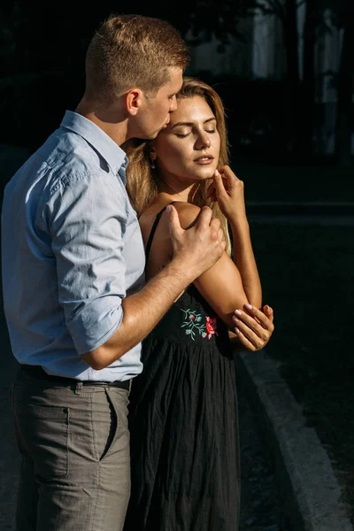 adam öpücük bir kız onu, sarılma, sokaklarda birbirine çekti. siyah bir dress.man kız arkasından kadın hugs ve alnından öper