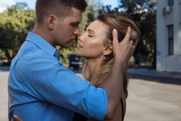 En man kramar en tjej och vill kyssa, fingrarna i hennes hår, rätar ut håret. Stor plan. Par Kyssar på street.passion och attraktion — Stockfoto