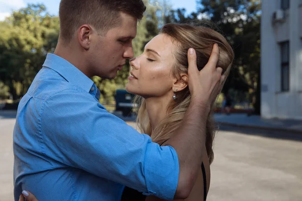 Een man een meisje knuffels en wil kiss, vingers in haar haar, rechtzetten haar haar. Grote plan. Paar kussen op de street.passion en de aantrekkingskracht — Stockfoto