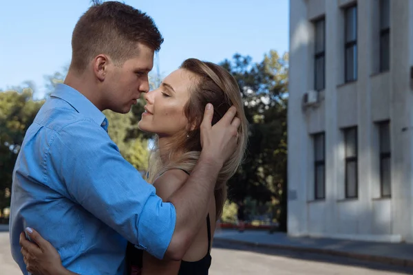 Een man een meisje knuffels en wil kiss, vingers in haar haar, rechtzetten haar haar. Grote plan. Paar kussen op de street.passion en de aantrekkingskracht — Stockfoto