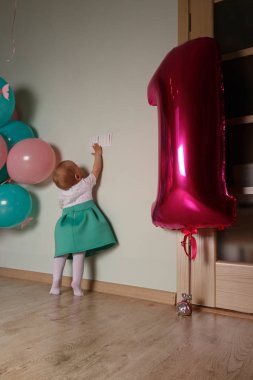 küçük çocuk ulaşan ilk Doğum günü balonları, yakındaki bir ışık düğmesi için. Curiosity.Girl beyaz bir mavi elbiseli