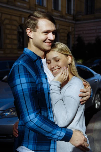Portrait of a happy couple hugging in the street, in the city.standing in better from the sun, hard light. date — Stock Photo, Image