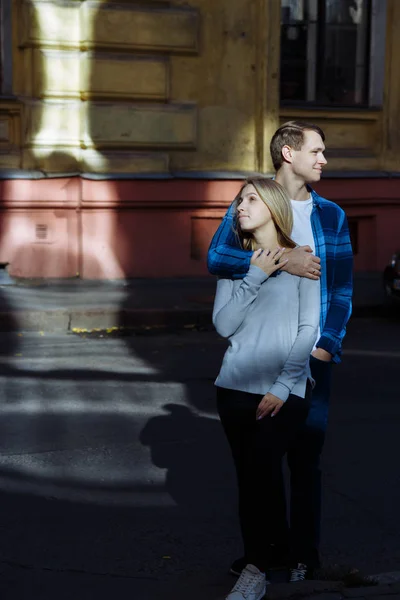 Portret szczęśliwa para, przytulanie na ulicy, w city.standing w lepszy od słońca, Ostre światło. Date.The słońce świeci na twarzach, promienie słońca między mężczyzną i kobietą, pocałunek — Zdjęcie stockowe