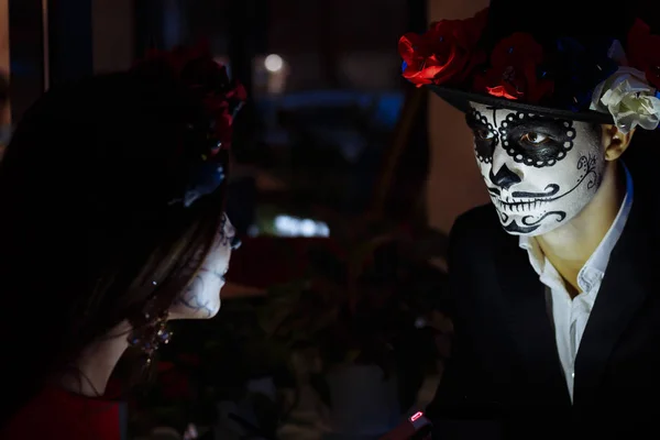 Santa Muerte. couple in the dark with a halloween make-up, face blessed with cold light. Party