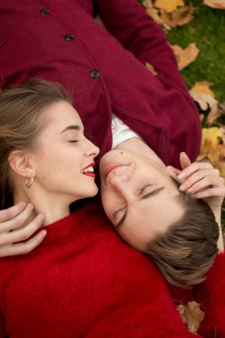 Bir kız ve bir adam kırmızı kazak, başkanları, dudak yakın, sevgi ve cazibe bir close-up. kiss.love ikinci bir tarih. Çift sarı yapraklarda yatıyor