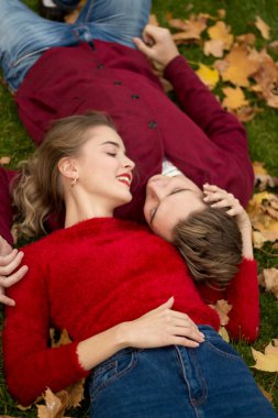 bir çift sarı akçaağaç yaprakları yeşil çim üzerinde yalan söylüyor, yüzlerini birbirlerine, bir tarih, aşık, evli bir çift, bir sonbahar roman, attraction.relaxation yakın