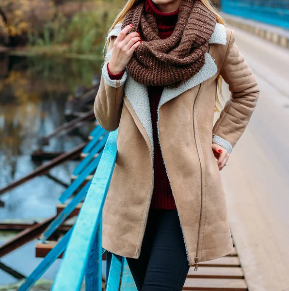 Дівчина в коричневій куртці біля річки і коричневий шарф, сніг. осінь, в'язані речі, ручна робота , — стокове фото