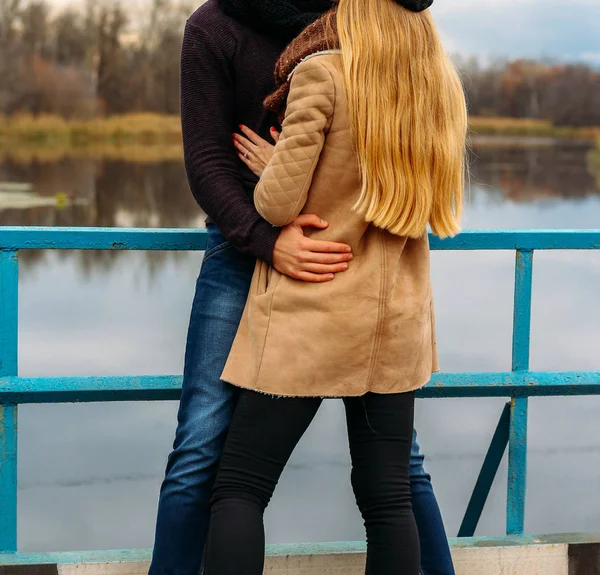 Paar umarmt auf der Brücke, in der Nähe des Wassers, Herbst. Liebe und Familie, ein Date im Park am Fluss — Stockfoto