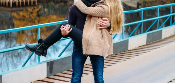 Couple on the bridge, the guy holds the girl in his arms, hug, near the water, autumn. love and family, a date in the park by the river — Stock Photo, Image