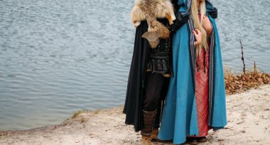 bir kız bir mavi pelerin ve bir adam eski giysiler, üniformalar, koruma. nehir, hugs, Çift, tutum dur. Cosplay tahtlar. wolfskin pelerin. kıyafet