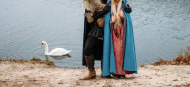 bir kız bir mavi pelerin ve bir adam eski giysiler, üniformalar, koruma. nehir, hugs, Çift, tutum dur. Cosplay tahtlar. wolfskin pelerin. kıyafet