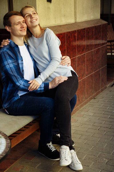 happy couple sitting outdoors in a cafe, the girl in the arms of the guy. smiling.at the table