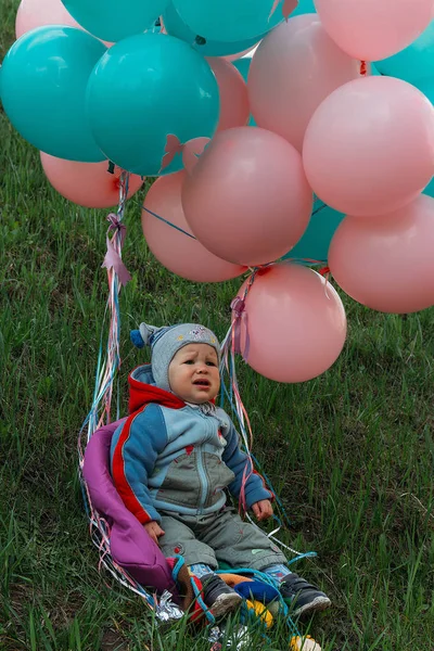 a little girl, a child, sits on the floor and cries, wrinkled her nose, near the balloons, a holiday. birthday, turned a year old. dress is white and blue. resentment, disappointment.the child cries, gets angry.frustrated baby. cry