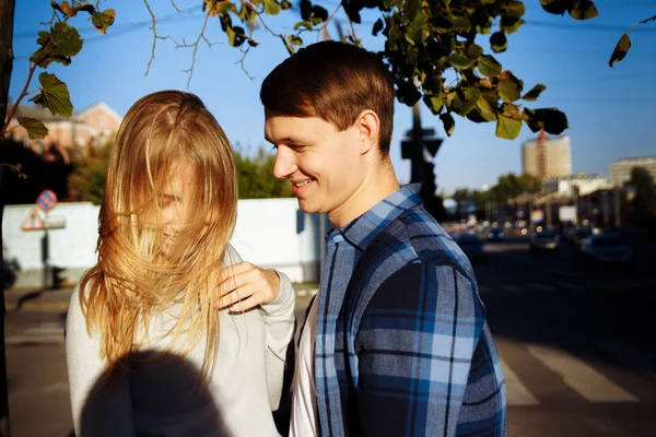 Ευτυχισμένο ζευγάρι χαζεύεις στην πόλη, τα κορίτσια τα μαλλιά πήρε στο πρόσωπό της, ο τύπος είναι χαμογελαστός — Φωτογραφία Αρχείου