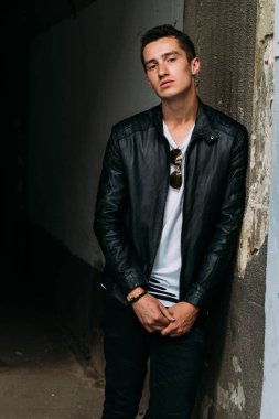 Genç, yakışıklı beyaz tişört, siyah, deri ceket ve siyah pantolon sokak, n T-shirt güneş gözlüğü biri. modeli, şehirde yürümek, canlı stil