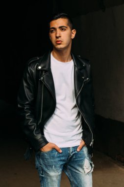 Genç, yakışıklı bir beyaz gömlek, siyah, deri ceket ve mavi, yırtık kot biri sokak, modeli, şehirde yürümek, canlı Style.in'ın beyaz spor ayakkabı