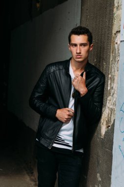 Genç, yakışıklı beyaz tişört, siyah, deri ceket ve siyah pantolon sokak, n T-shirt güneş gözlüğü biri. modeli, şehirde yürümek, canlı stil