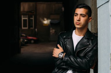 Genç, yakışıklı bir beyaz gömlek, siyah, deri ceket ve mavi, yırtık kot biri sokak, modeli, şehirde yürümek, canlı Style.in'ın beyaz spor ayakkabı