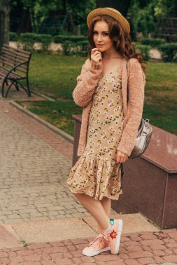 Romantik kız elbise ve sıcak renkler bir kazak giyiyor şehirde, saçları rüzgarda geliştirir. gülümseyen ve başım dönüyor. şapkasını devam ediyor