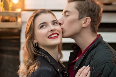 kız ve kırmızı kazak ve kot giyen kız smiles.a tarihi sonbaharda sarı akçaağaç yaprakları yeşil çimenlerin üzerinde parkta oturup.