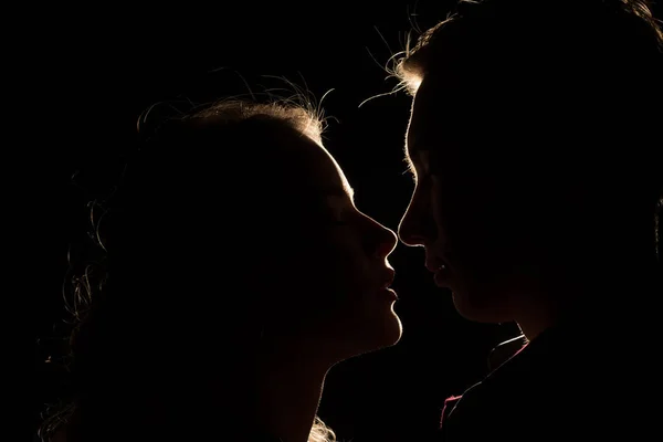 black background, couples, heads, between them a light, a ray of light unfinished kiss.the beginning of a kiss.