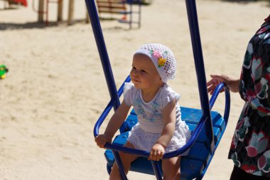 küçük bir kız bir kızın kollarında oturur, o arka ve tutan elleri sarıldı.