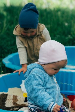 iki çocuk kum havuzunda oturup oynamak kürek, Tırmıklar, oyuncaklar ile