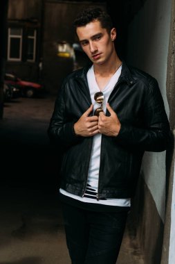 Genç, yakışıklı beyaz tişört, siyah, deri ceket ve siyah pantolon sokak, n T-shirt güneş gözlüğü biri. modeli, şehirde yürümek, canlı stil