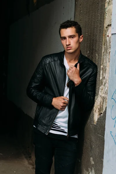 young, handsome guy in a white T-shirt, black, leather jacket and black pants is on the street, n the T-shirt sunglasses. model, city walk, live style