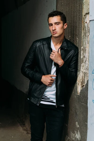 young, handsome guy in a white T-shirt, black, leather jacket and black pants is on the street, n the T-shirt sunglasses. model, city walk, live style