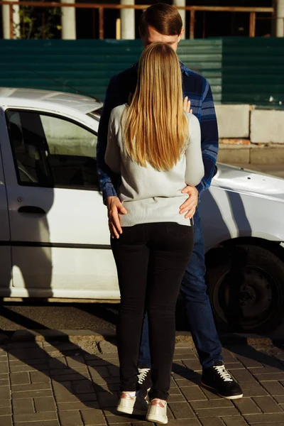 the guy hugs the girl for the waist, the girl bowed her head, crying or smiling. date or parting. the end of the relationship. happy couple over city,road and cars background.