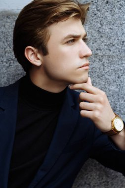 Şehrin üzerinde el, altın bilek watch.pensive gri background.watch üzerinde mavi elbiseli çekici bir genç adam portresi